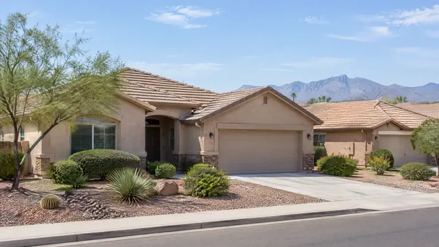 Single-story stucco homes with tan concrete tile roofs and rock front yards in an east Chandler neighborhood, mountains faint in the distance