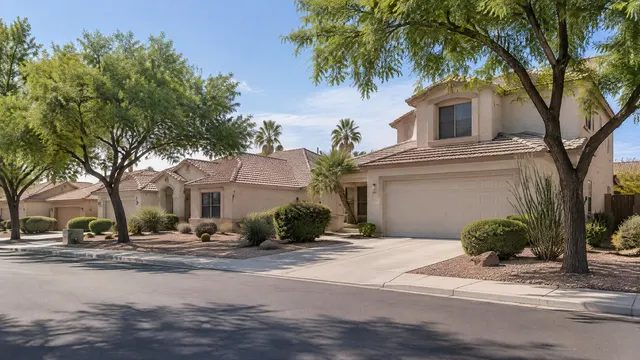 Quiet residential street of 1990s single-story and two-story stucco homes with brown flat concrete tile roofs and mature shade trees in west Chandler