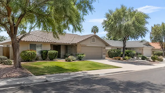 Established single-story ranch homes with low-pitch roofs, some shingle and some tile, mature trees and grass yards in a 1980s Chandler neighborhood